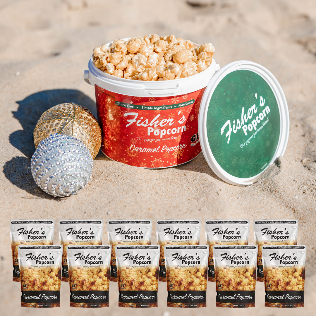 A tub of BYOB Office Party Pack caramel popcorn sits on sand with its lid propped up, two ornaments beside it, and eight smaller caramel popcorn bags in front—perfect as an office gift or festive holiday bundle.