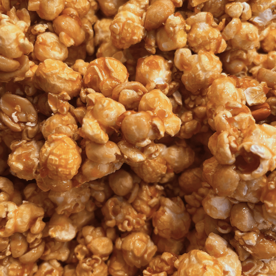 Close-up of Fisher’s Popcorn Tubs by Fisher's Popcorn, featuring glossy, golden-brown caramel popcorn pieces clustered together in the tub for an appetizing, textured look.