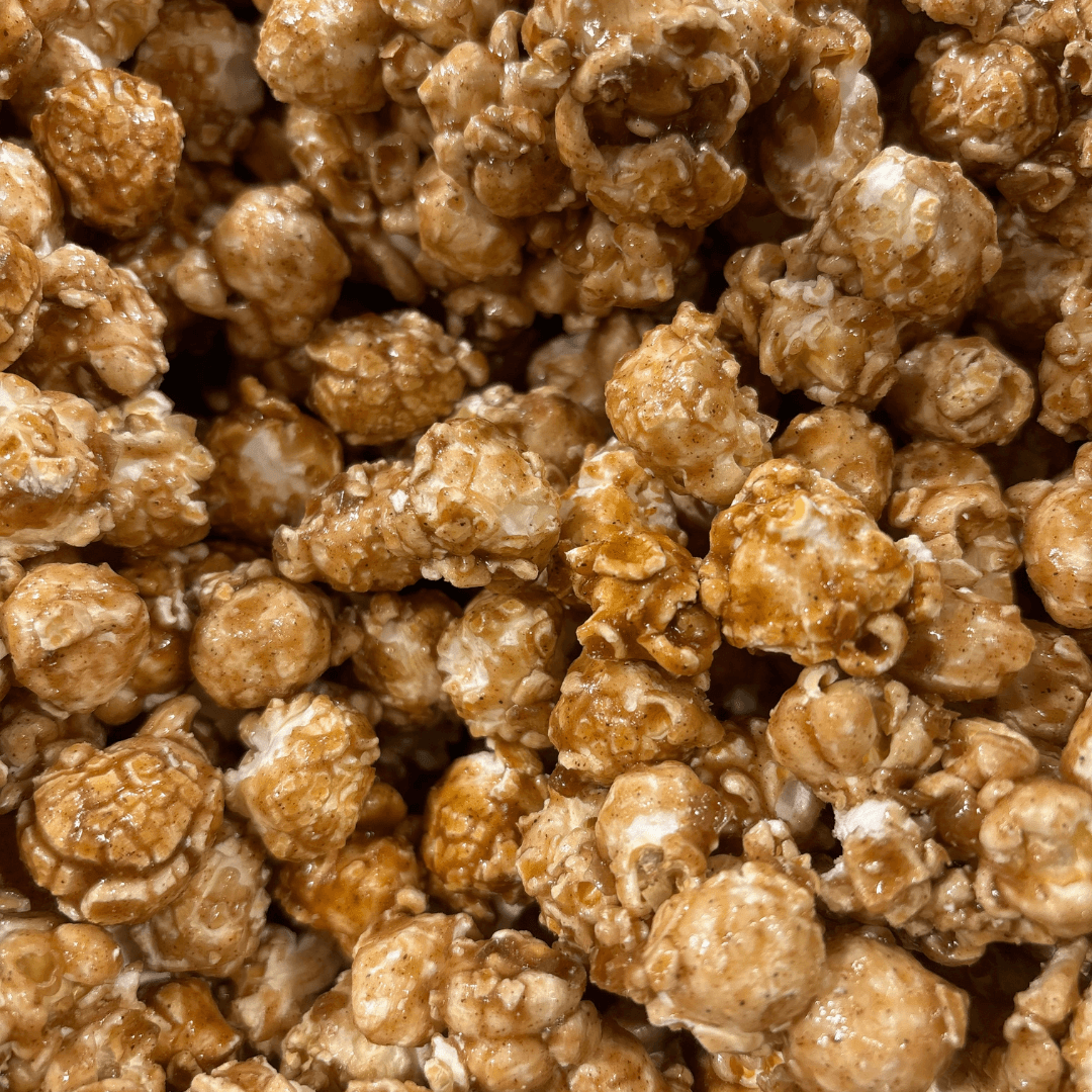 Close-up of Fisher's Popcorn Tubs original caramel popcorn pieces clustered together, highlighting their glossy, golden-brown coating and textured kernels—ideal for snacking fresh from the tub.