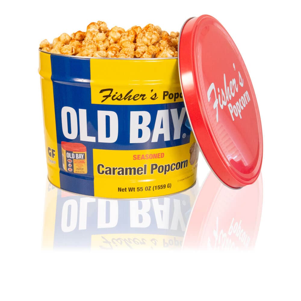 A large blue and yellow 2 Gallon OLD BAY® Tin by Fisher's Popcorn, with the lid propped aside to reveal OLD BAY® seasoned caramel popcorn inside. Both lid and tin display the Fisher’s Popcorn branding.