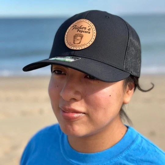 Woman in a black Fisher's leather-patch trucker hat on the beach